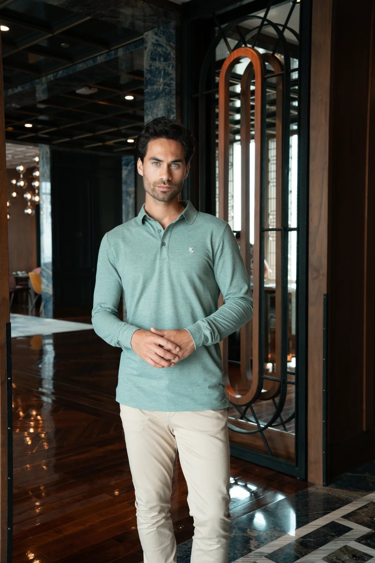 Raphael Korse in een groene polo en lichte broek in een donker interieur