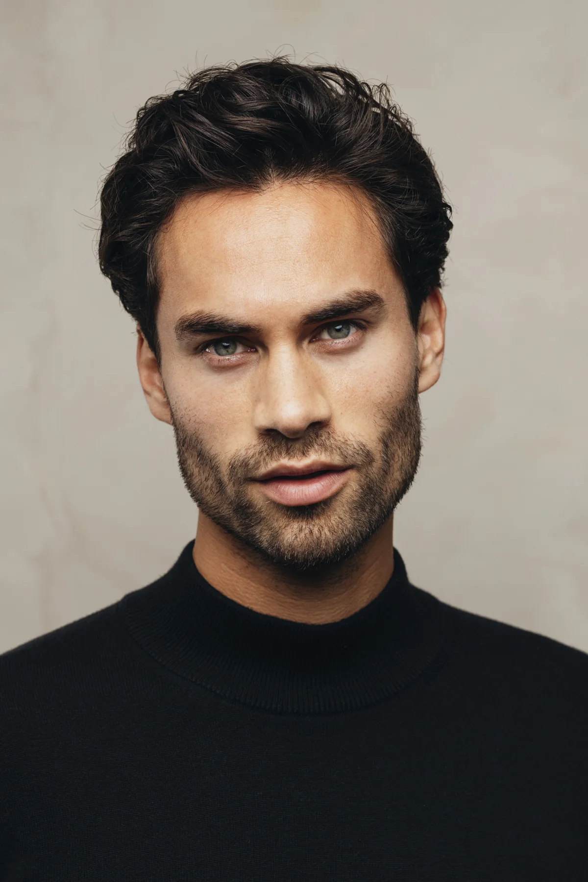 Portret van Raphael Korse in een zwarte coltrui tegen een lichte achtergrond